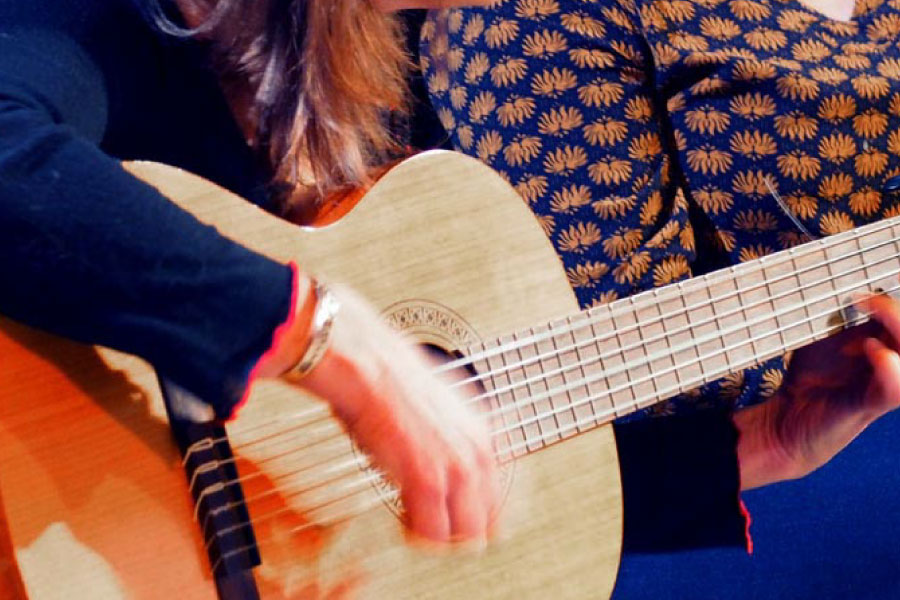 Élève jouant de la guitare classique, avec une illustration de guitare acoustique superposée.